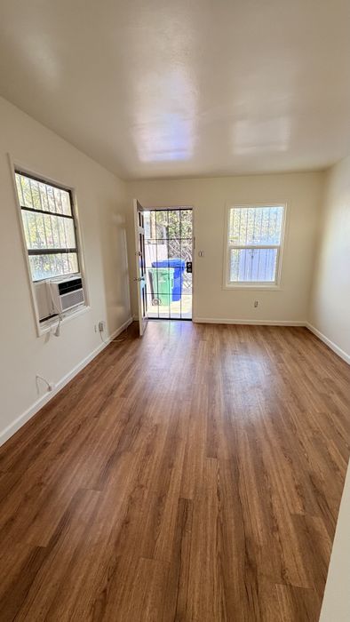 Living space with wooden floors, AC unit, and window.