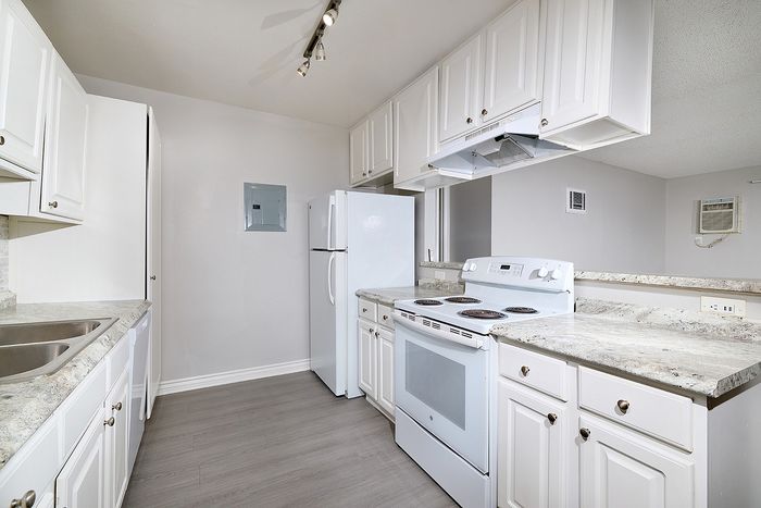 Unstaged kitchen with counters, cupboards, oven, sink, and lighting.