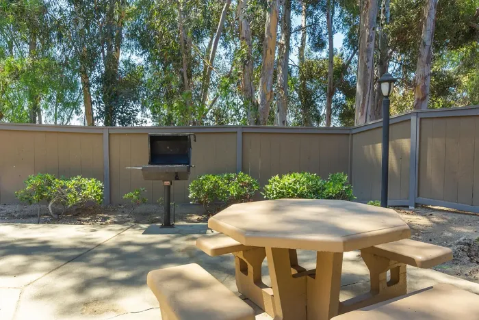Outdoor BBQ area with picnic table and trees at Elan - Scripps Terrace.