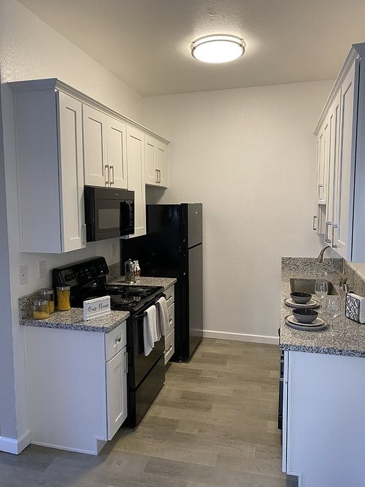 Kitchen with white cabinetry and dark appliances at Elan - Terraza La Jolla