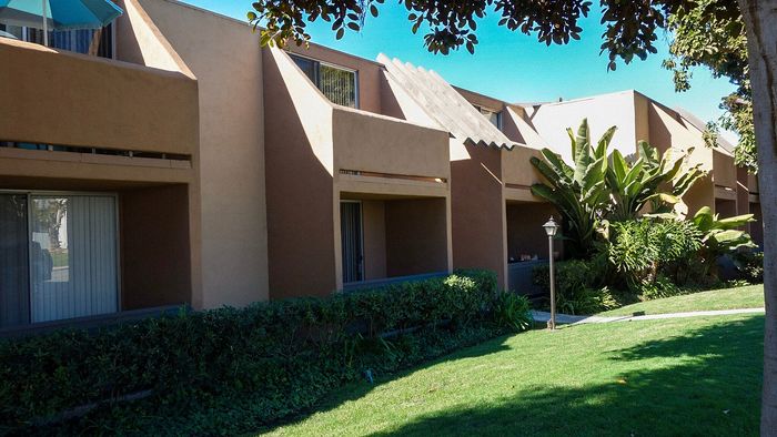 Modern apartment exterior with lush green landscaping at Elan - Sandpiper Del Mar