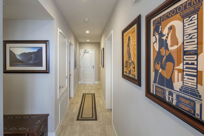 Elegant hallway with framed art leading to modern living spaces at Elan - Luxo II.