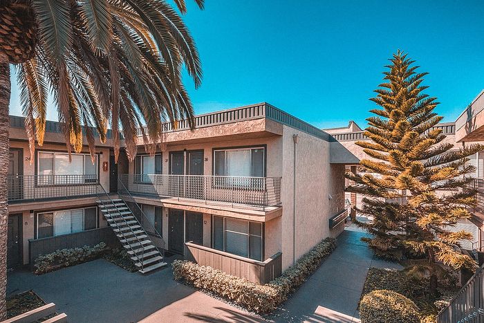 Scenic courtyard with palm trees and multi-level apartments at Elan - Sandrock Place
