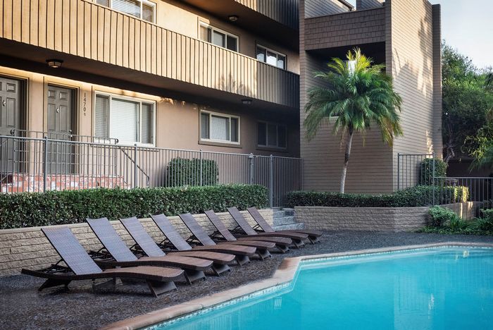 Relaxing poolside lounge deck with wooden sun chairs at Elan - Baylofts