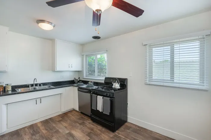 Modern kitchen with white cabinetry and black appliances at Elan - Baylofts