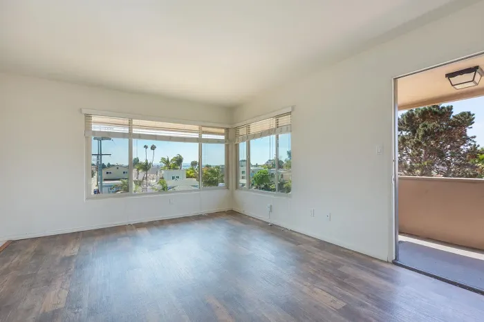 Open living space with wood-style flooring and balcony access at Elan - Baylofts