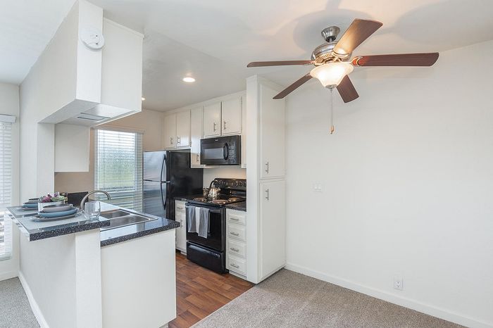 Kitchen featuring a breakfast bar, ceiling fan, and dark appliances at Elan - pacific lofts