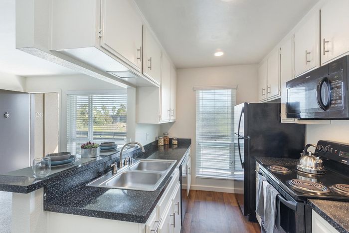 Modern kitchen with black appliances and granite-style counters at Elan - pacific lofts