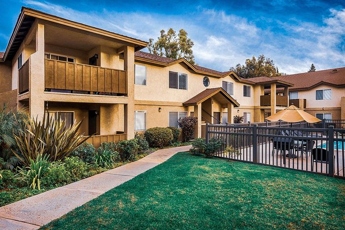 Two-story apartment exterior with lush green landscaping at Elan - poway hills.