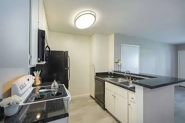 Modern kitchen with granite-style counters and black appliances at Elan - poway hills.