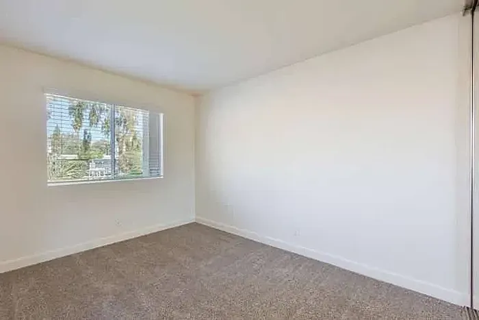 Spacious bedroom with a large window and neutral carpet at Elan - poway hills.