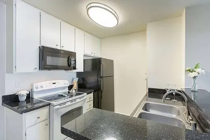 Fully equipped kitchen with black appliances and white cabinets at Elan - poway hills.