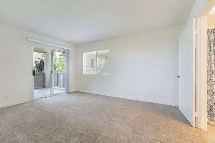 Sunlit living room with plush carpet and balcony access at Elan - poway hills.