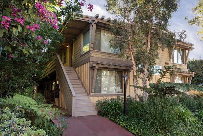 Multi-story building with blooming purple flowers at Elan - beachcomber la jolla.
