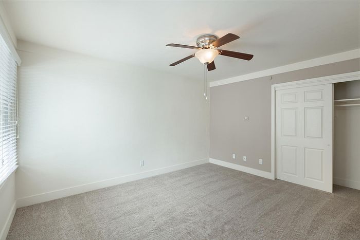 Spacious bedroom with plush carpet and a ceiling fan at Elan - beachcomber la jolla.