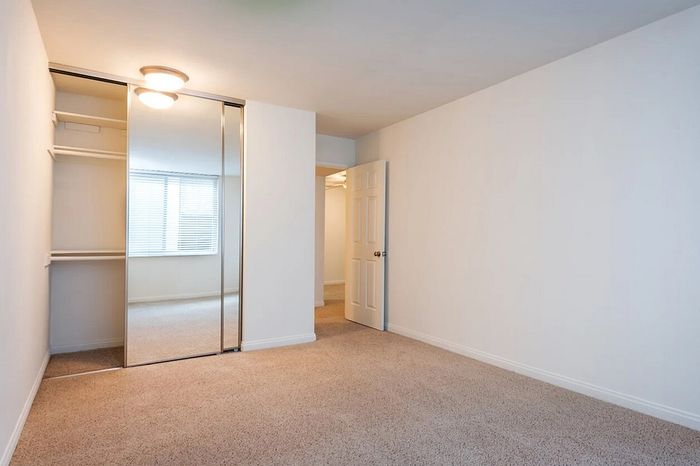Bright bedroom with mirrored closet doors and built-in shelves at Elan - bella mer coronado.