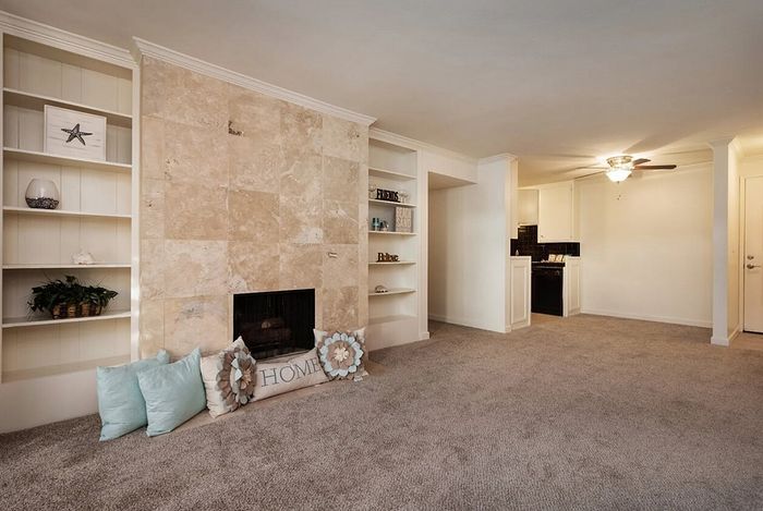 Living room with a cozy fireplace and built-in shelving at Elan - bella mer coronado.