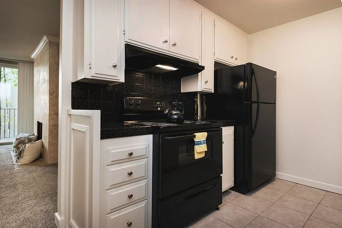 Modern kitchen with black appliances and white cabinetry at Elan - bella mer coronado.