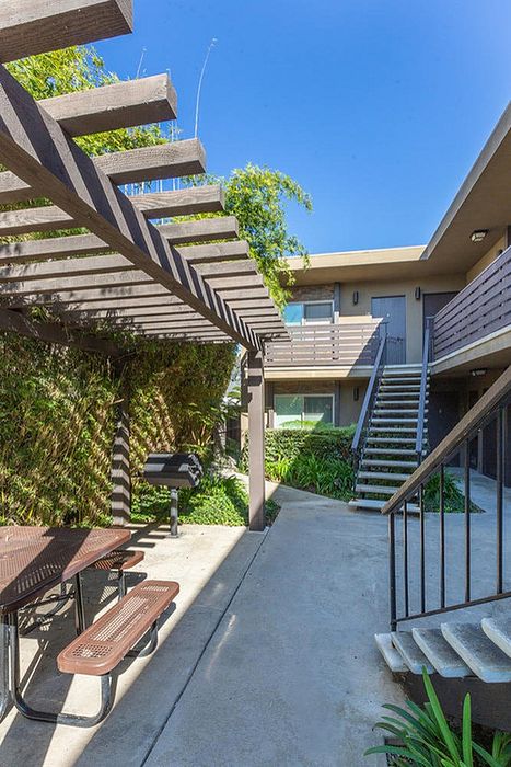 Shaded courtyard walkway with a wooden trellis and bench at Elan - beachlofts del mar