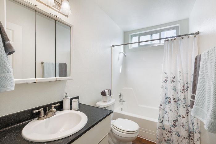 Bathroom with a dark vanity, white sink, and tub-shower at Elan - beachlofts del mar