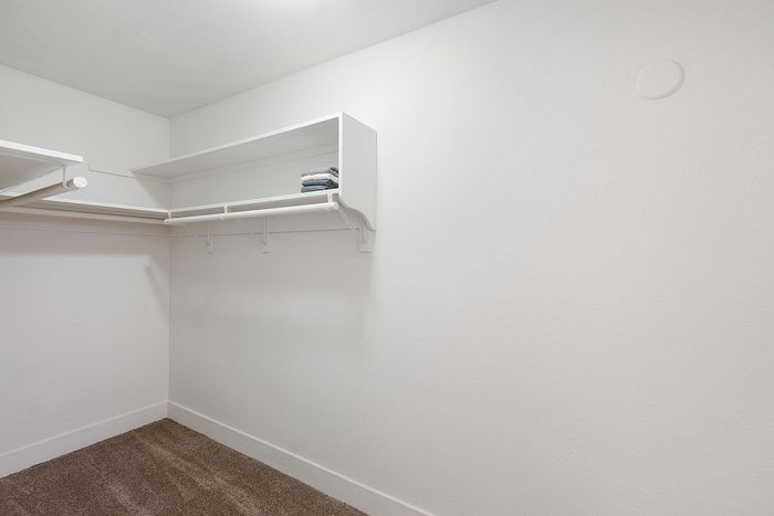 Spacious walk-in closet featuring built-in white shelving at Elan - beachlofts del mar
