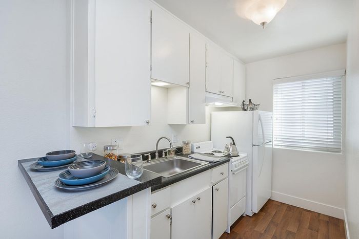 Modern kitchen with white cabinetry and dark countertops at Elan - beachlofts del mar