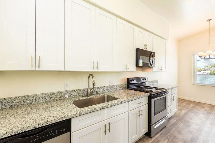 Modern kitchen with white cabinets and dark appliances at Elan - beachhouse del mar