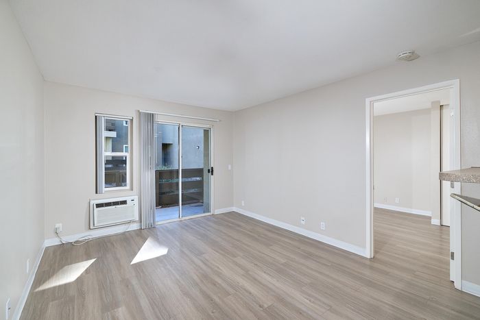 Living space with balcony view, wooden floors, and AC