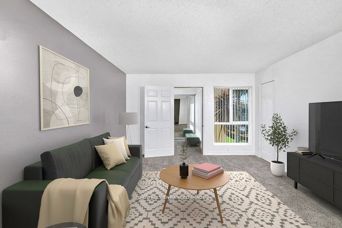 Virtually staged two bedroom at Pine Vista showing the living room with a couch, tv and rug