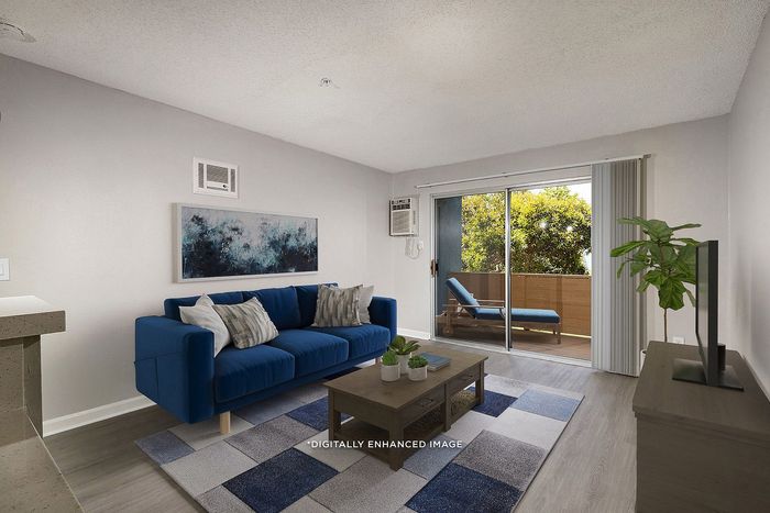 Virtually staged living room with sofa, rug, coffee table, tv, patio, and plant.