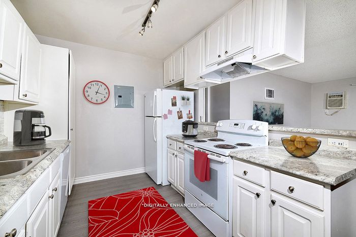 Virtually staged kitchen with mat, oven, fruit bowl, crockpot, fridge, clock, coffee maker, sink, countertops, cupboards, and lighting.