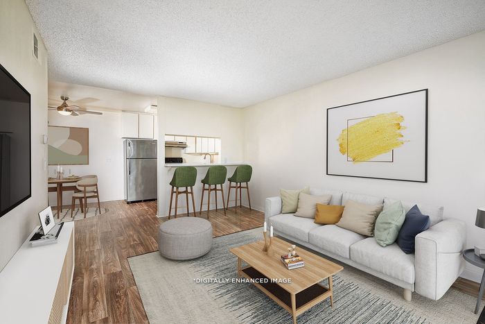 Virtually Staged Image - Open living room and dining area with ceiling fan and wood-style vinyl plank flooring