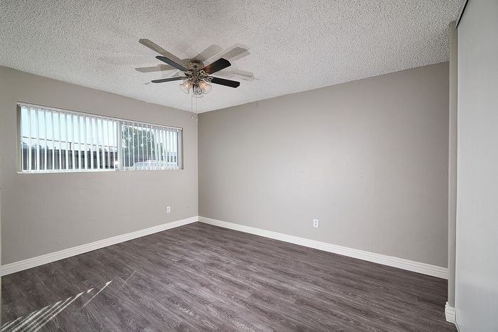 Spacious bedroom with ceiling fan, mirrored closet doors