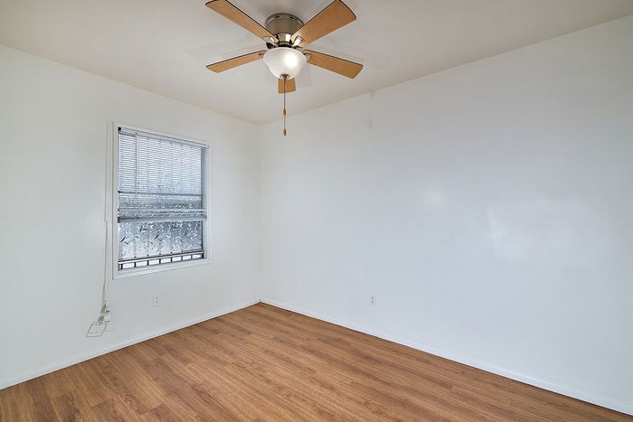 Bedroom with fan, window, and wooden floor