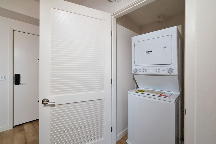 In-unit laundry closet at textur apartments featuring a stacked white washer and dryer behind a louvered door.