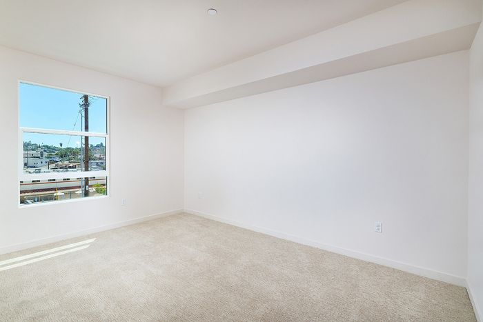 La Mesa apartment bedroom at textur with beige carpeting, clean white walls, and a window providing natural light.