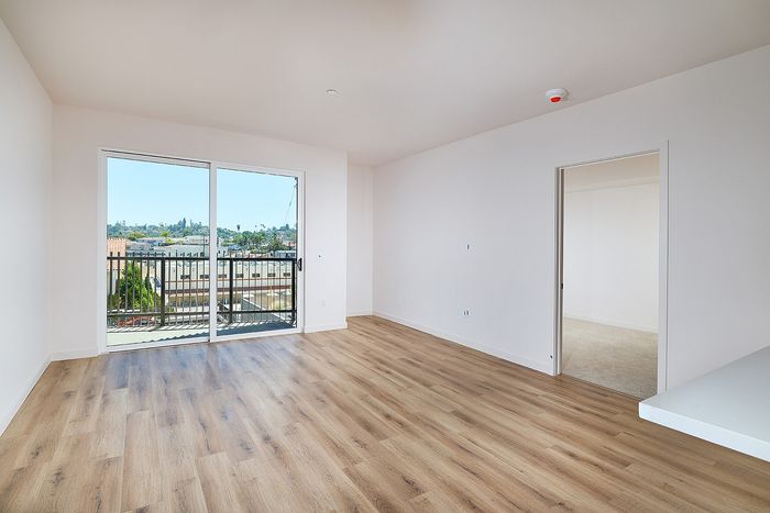 Spacious two-bedroom apartment living room at textur with wood-style flooring and sliding glass door to a balcony.