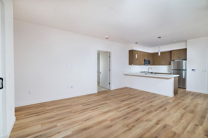 Open-concept living room and kitchen at textur apartments in La Mesa featuring wood-style plank flooring.