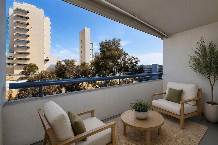 virtually staged-Covered apartment balcony with patio chairs and olive tree at The Warwick Apartment Homes.