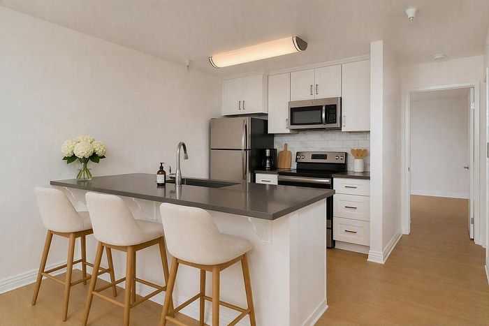 virtually staged-Apartment kitchen peninsula with barstool seating and dark quartz counters at The Warwick.
