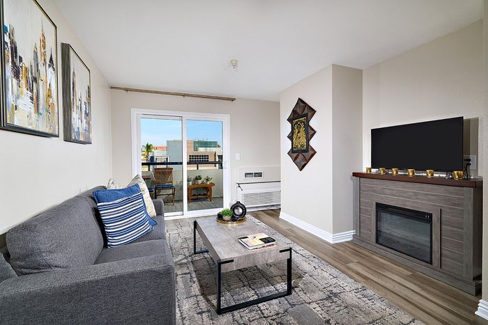 Living room with grey sofa, rug, and sliding patio door at The Warwick Apartment Homes.