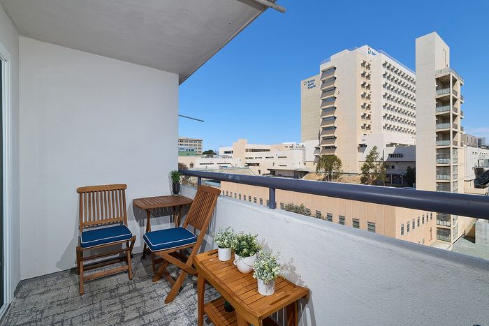 Private apartment balcony with wooden patio chairs at The Warwick Apartment Homes in San Diego.