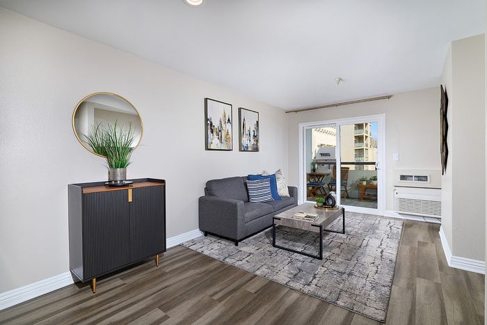 Living room interior with credenza cabinet and round mirror at The Warwick Apartment Homes.