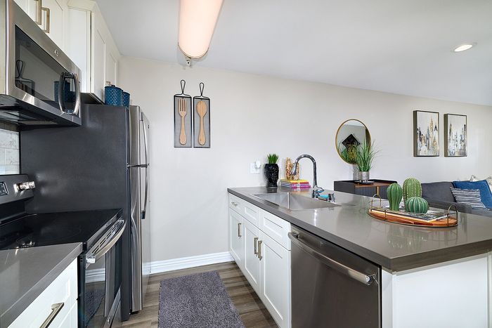Kitchen island bar with dark quartz countertops and sink at The Warwick Apartment Homes.