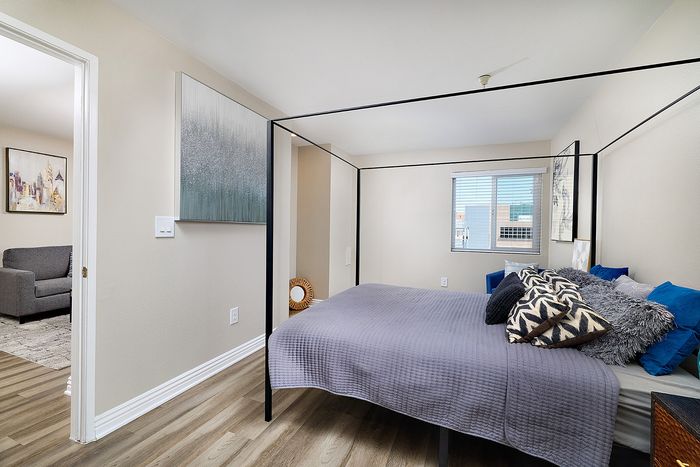 Bedroom with wood-style flooring and natural window light at The Warwick Apartment Homes.