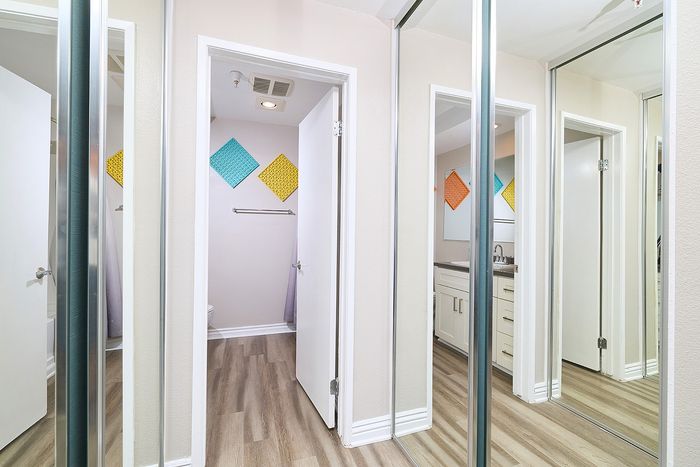 Bedroom closet hallway with mirrored sliding door storage at The Warwick Apartment Homes.