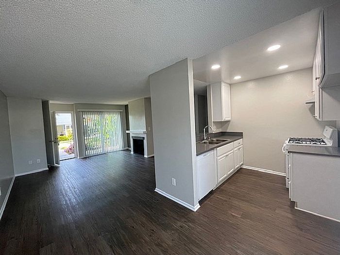 Open living area with wood plank flooring, fireplace, and kitchen at Delaware Pines Apartments.