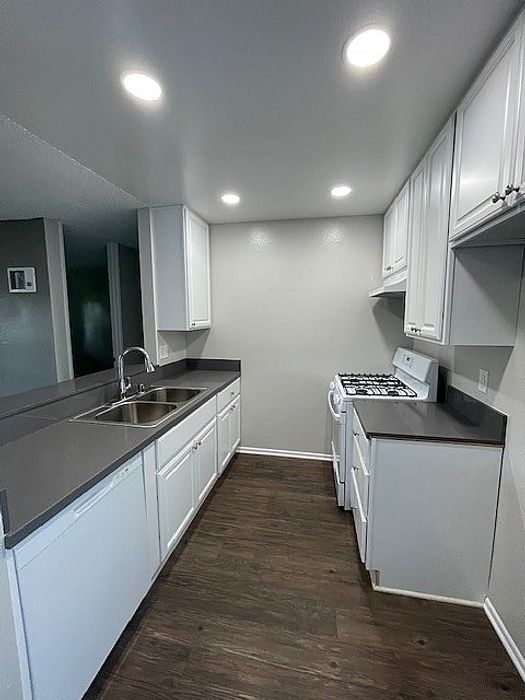 Modern kitchen with white cabinetry, dark quartz countertops, and gas stove at Delaware Pines.