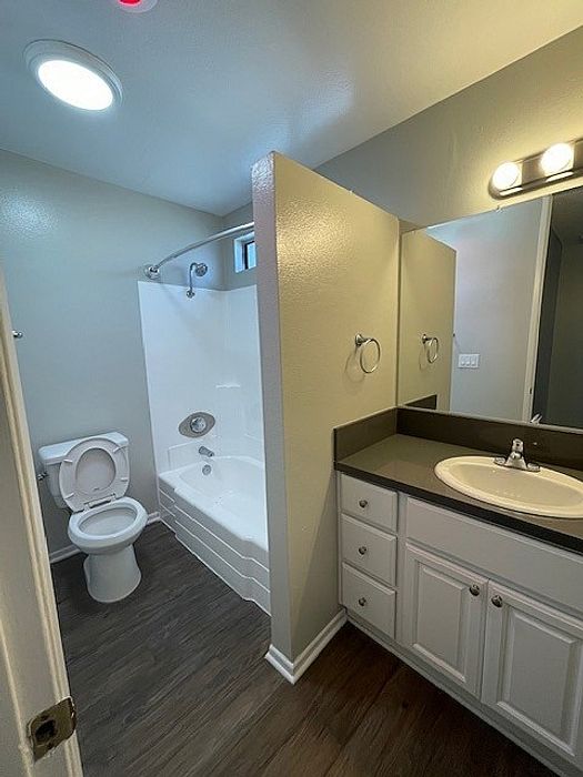 Bathroom with white vanity, dark countertop, mirror, and bathtub at Delaware Pines Apartments.