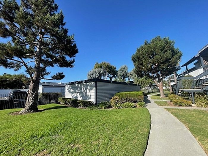 Paved walkway running past garages and pine trees at Delaware Pines.